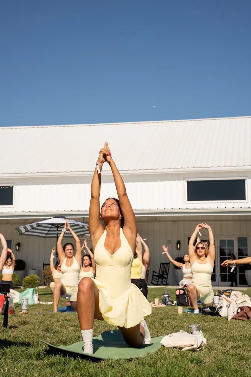 A yoga class on a lawn with an instructor leading the pose